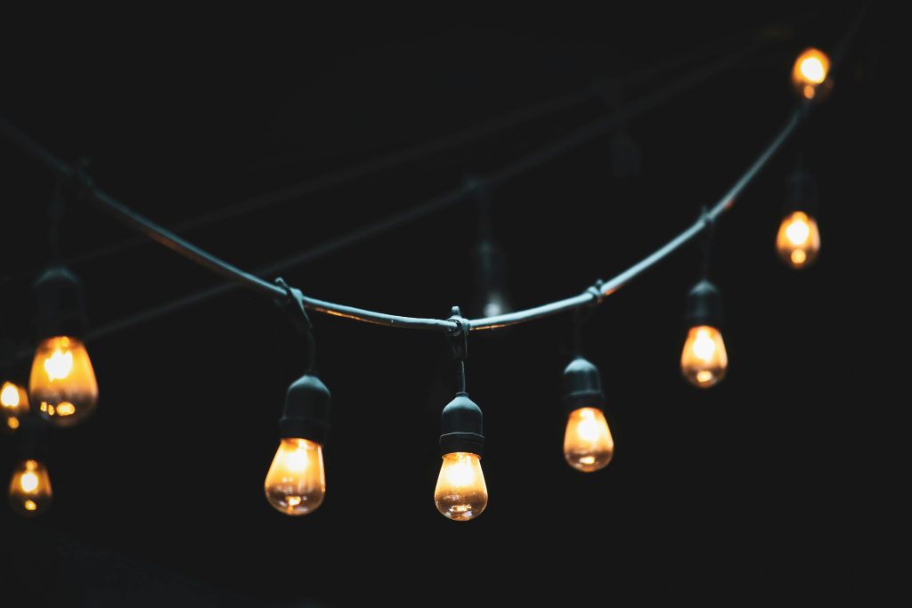 Close-up of glowing string lights against a dark background, creating a warm ambiance.