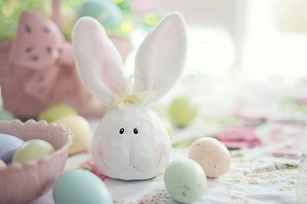 Charming Easter setup featuring a bunny decoration and pastel eggs on a floral tablecloth.