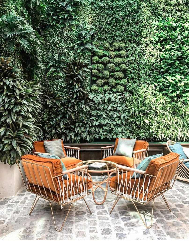 Charming outdoor patio featuring lush vertical garden and elegant seating, offering a tranquil retreat.