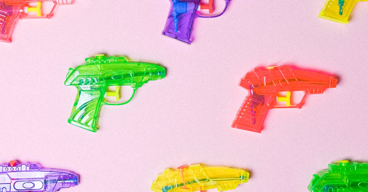 Colorful toy water guns on a pink background arranged in a pattern.
