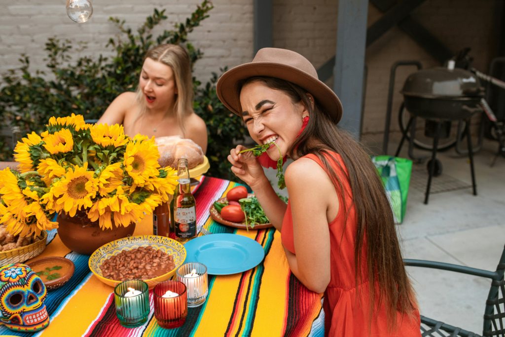 Cheerful women enjoying Mexican cuisine and decorations at an outdoor Cinco de Mayo party.