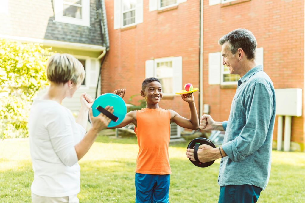 A joyful family enjoying time together playing with disc toys in their backyard.